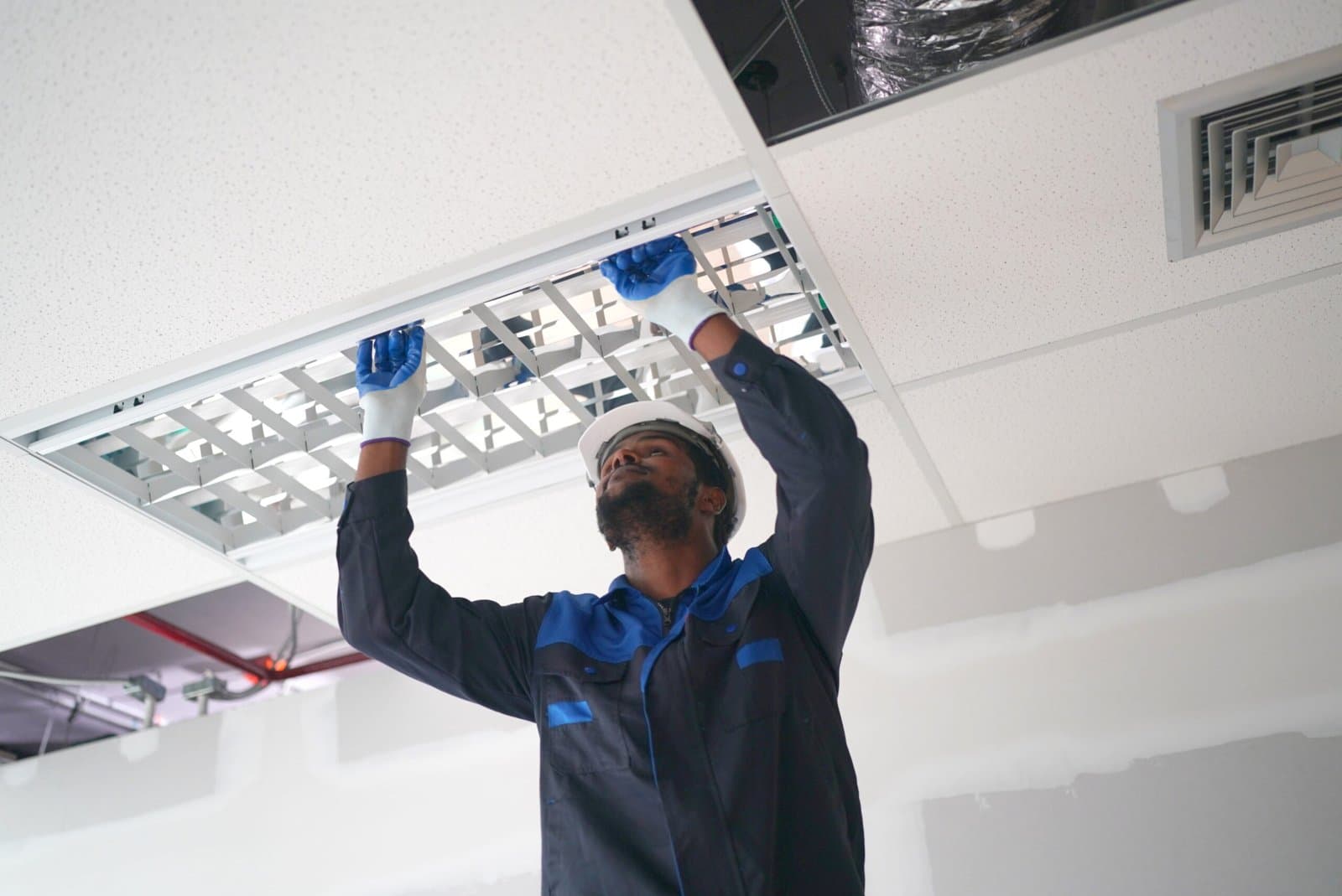Instalador colocando una luminaria en un techo técnico